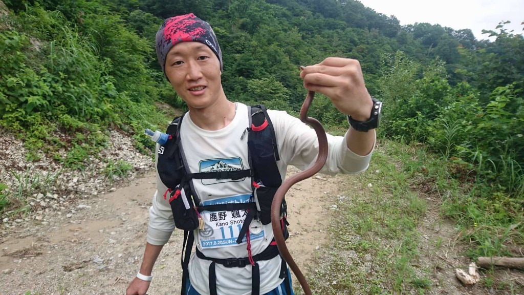 やにわにヘビを捕まえて観察する鹿野さん。